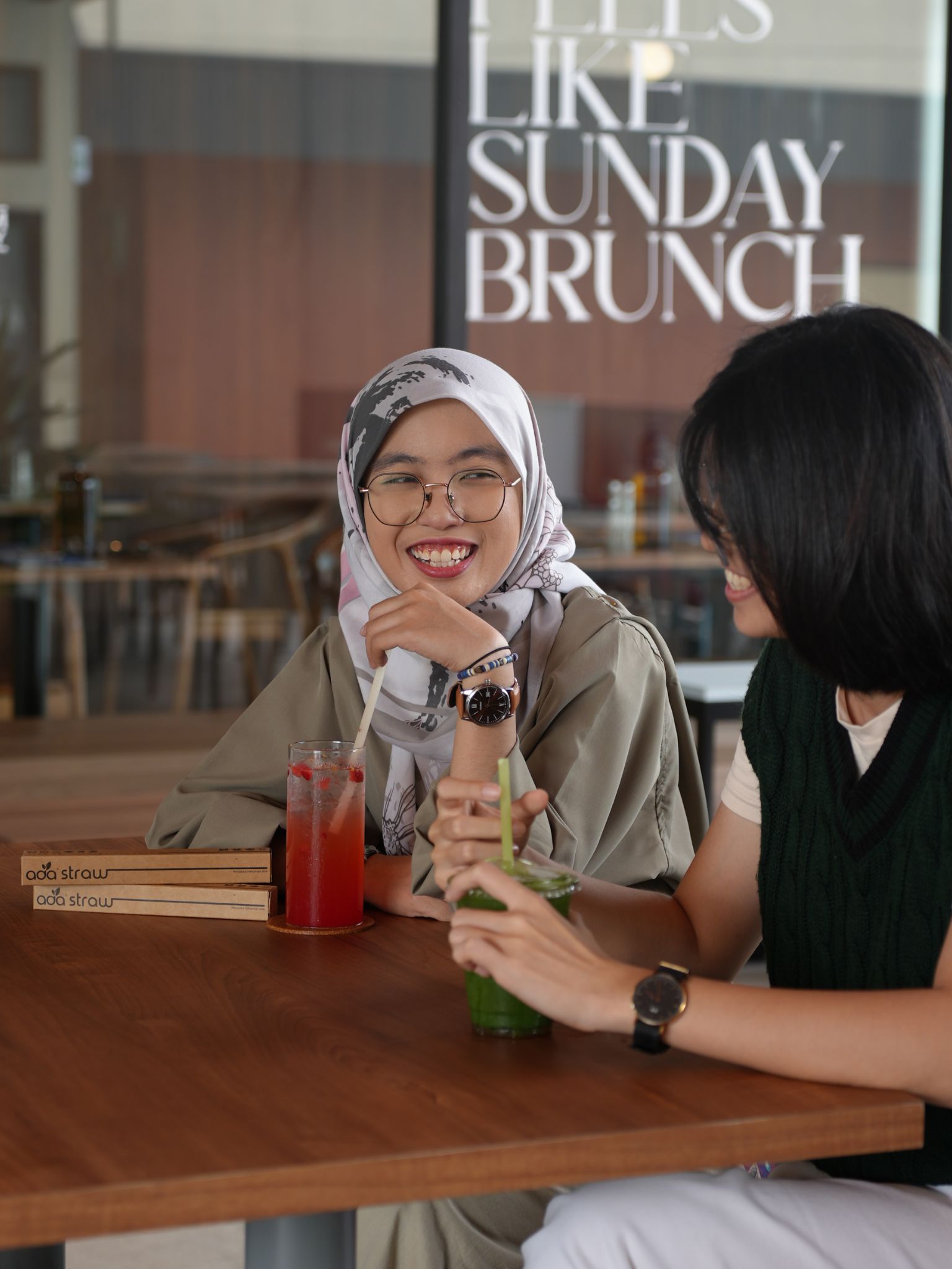 Two customers enjoying iced drinks served with ADA straws at a cafe table